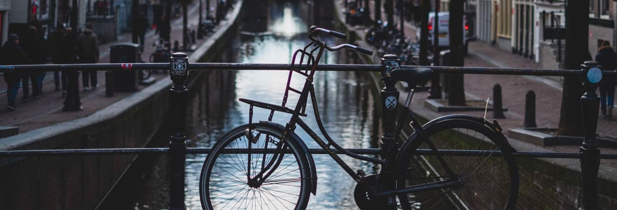 une bicyclette garée sur un pont au dessus d’un fleuve et entouré de bâtiments