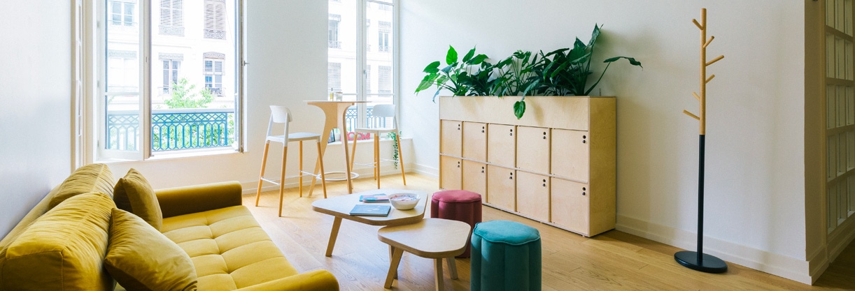 aménagement de l’espace de Malt avec du mobilier durable en bois : tables basses, casier de rangement, table haute pouf et canapé.