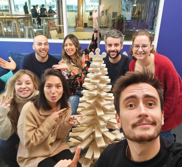 7 personnes heureuses autour d’un sapin fabriqué à la main à partir de chutes de bois de bouleau