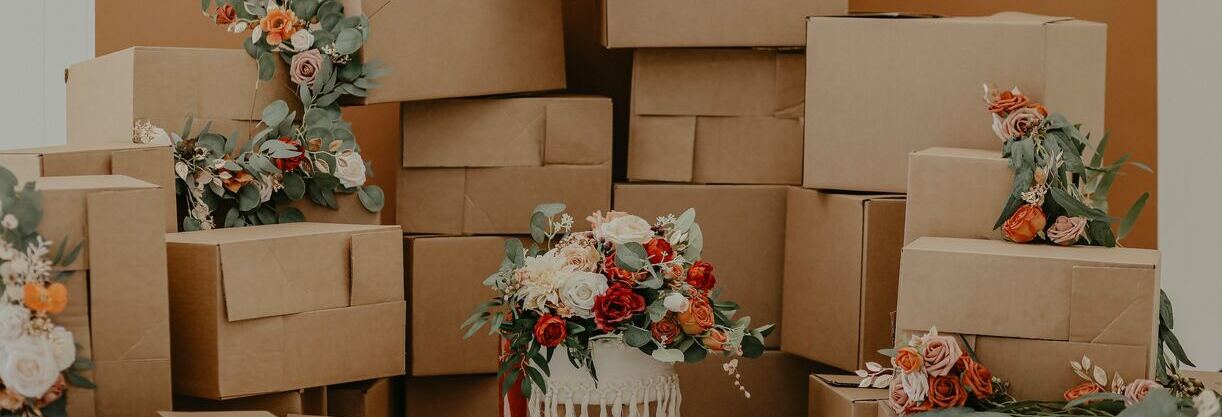 une quinzaine de cartons empilés avec des fleurs blanches, oranges et rouges posées dessus