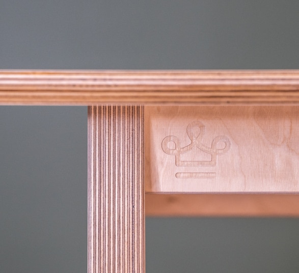 bout de table en bois vu de profil avec une courrone gravée sur le châssis