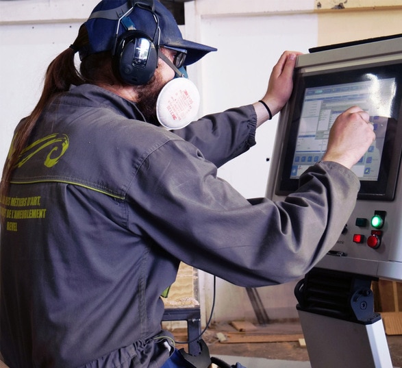 Homme en tenue de travail qui règle une machine de découpe du bois