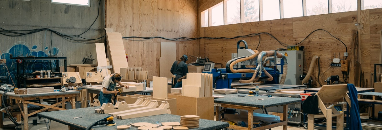 un atelier de fabrication de mobilier de bureau en bois avec des établis et une machine CNC
