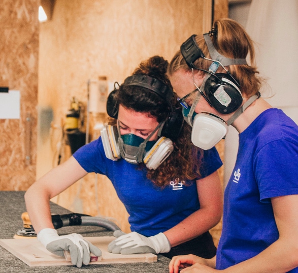deux ébénistes avec des tee-shirt bleu travaillent le bois sur le établis