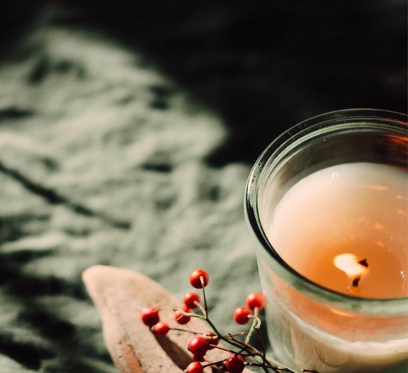 Une bougie blanche et des baies rouges sur une nappe kaki
