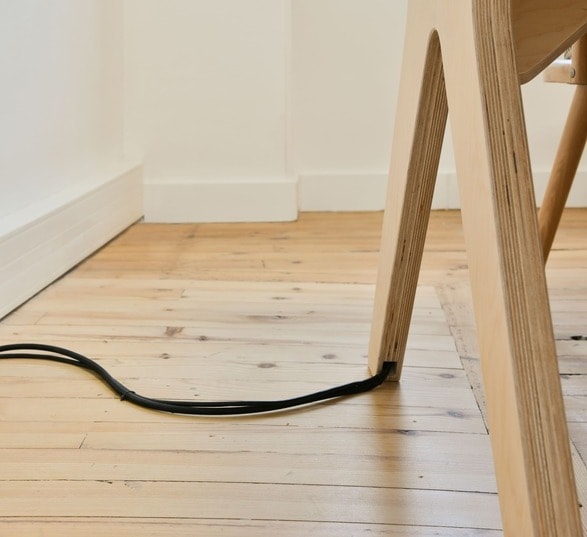 bureau en bois connecté avec un câble électrique qui sort du pied de la table