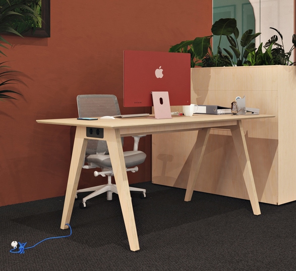 un écran d’ordinateur posé sur un bureau en bois moderne dans un open space d’entreprise