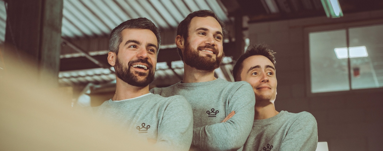 trois personnes sourient avec des pulls gris