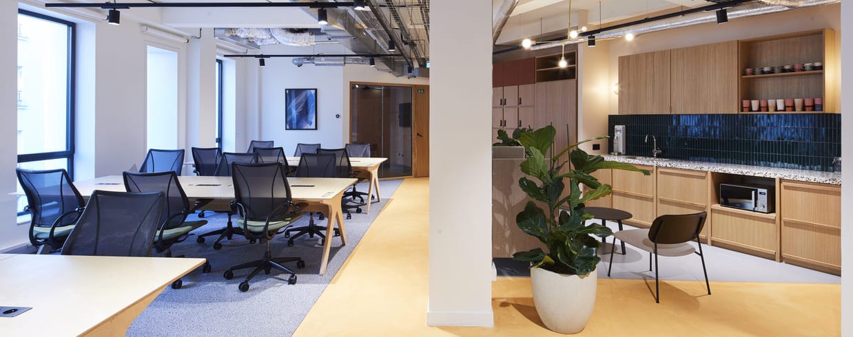 un espace de coworking design avec des bureaux à gauche et un espace cuisine à droite