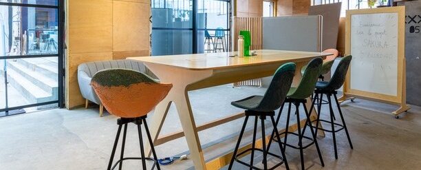 un espace de travail agréable avec table rectangulaire haute pour 6 personnes et un tableau blanc en bois
