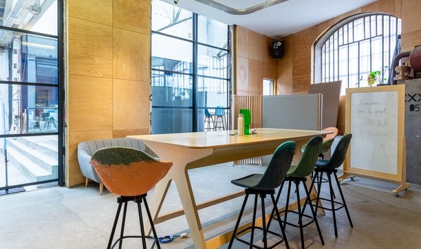 un espace de travail agréable avec table rectangulaire haute pour 6 personnes et un tableau blanc en bois