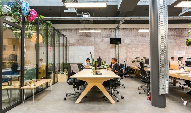 deux personnes travail sur un grand bureau en bois dans un espace de travail moderne et lumineux