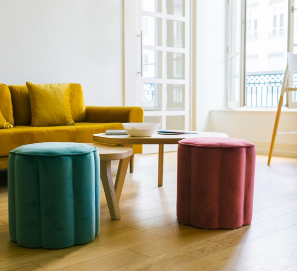 une salle de pause type salon avec poufs colorés, canapté jaune et table basse gigogne en bois