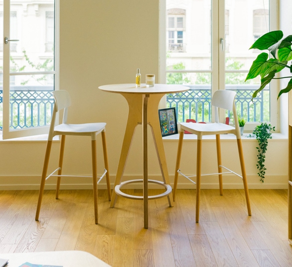 une table haute ronde avec deux chaises devant une fenêtre