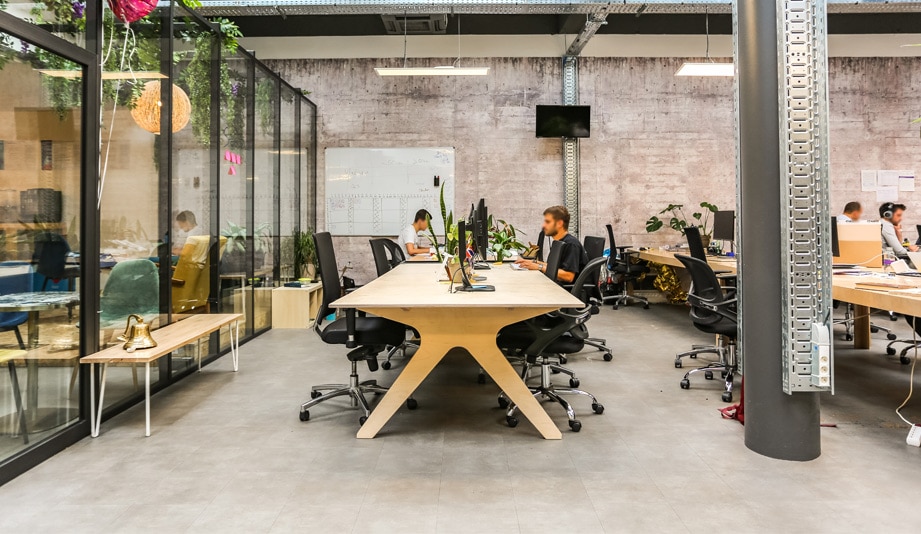 deux collaborateurs travails sur un grand bureau en bois dans un espace de travail style industriel à paris