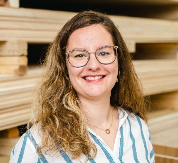 Jeune femme avec des lunettes et une chemise rayée bleu dans une usine de bois