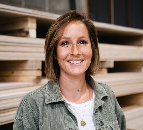 Jeune femme blonde souriante avec une veste verte dans une usine de bois