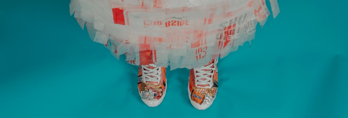 une personne vêtue d’une robe en plastique avec des chaussures oranges sur un sol bleu