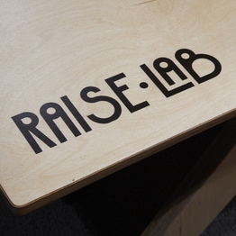 sérigraphie du logo raiselab sur une table en bois sur mesure
