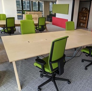 un open space avec bureaux en bois et sièges ergonomiques verts