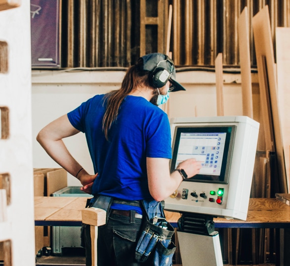 Un opérateur debout programme une machine CNC dans une usine de fabrication