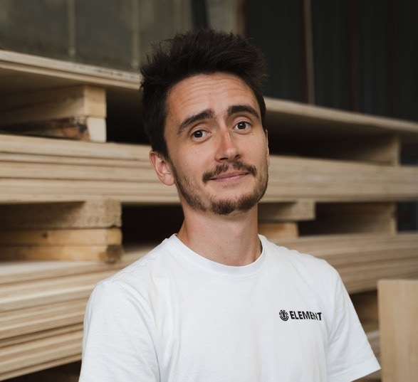 Homme avec une barbe portant un tee shirt blanc dans un atelier d’ébénisterie