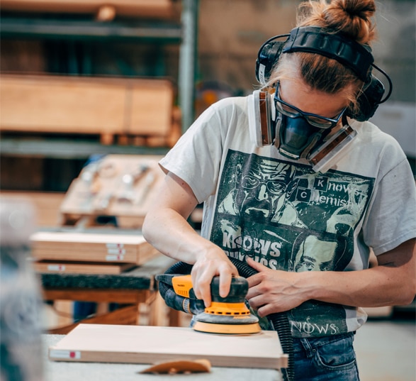 Ue femme ébéniste ponce une table de bureau dans un atelier