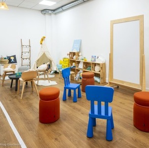salle de créativité pour enfants avec petits mobiliers colorés et tableau blanc en bois sur roulette