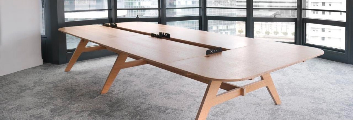 une table de réunion en chêne dans une grande pièce vitrée