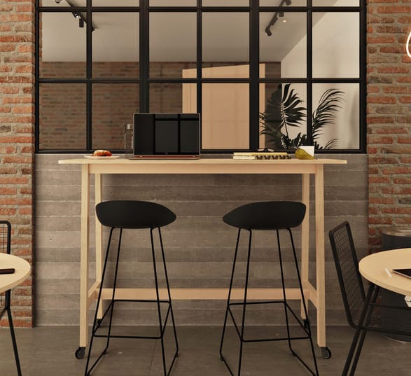 table haute rectangulaire en bois avec des chaises hautes noires devant un mur en brique