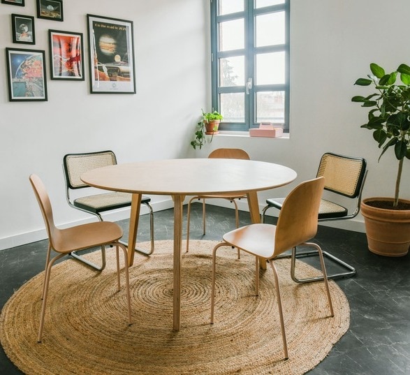 table ronde de réunion en bois avec quatre chaise, un tapis, des tableaux et une plante