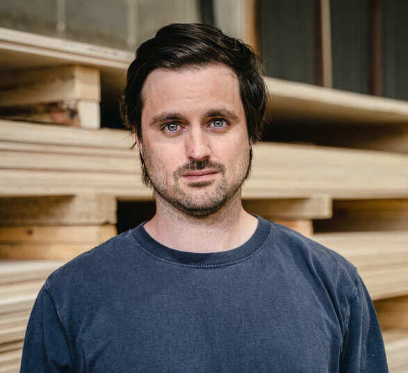 Homme brun avec une sweat bleu marine dans un atelier de fabrication de bois