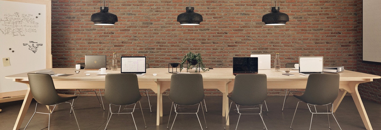 aménager une salle de réunion avec une table de réunion en bois, 5 chaises marron, un mur en brique et des luminaires industriels