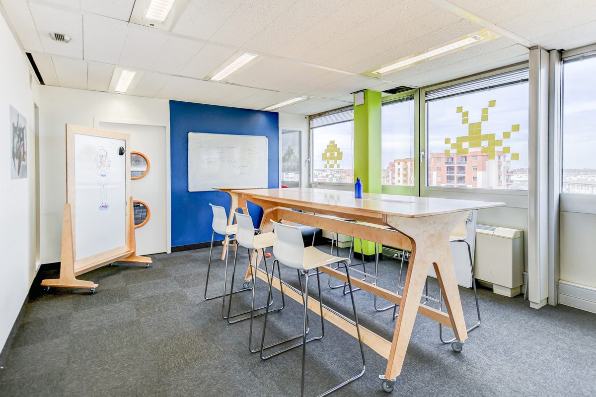 Salle de réunion coloré et lumineuse avec moquette grise meublés avec du mobilier ne bois clair