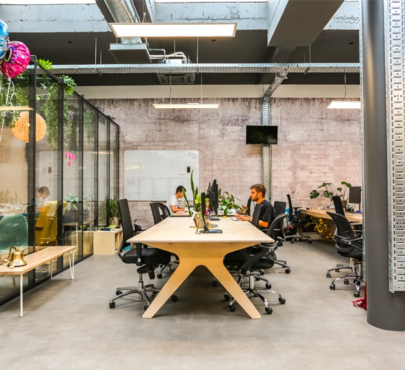 un bureau pour open space 6 places en bois avec deux personnes qui travaillent dessus