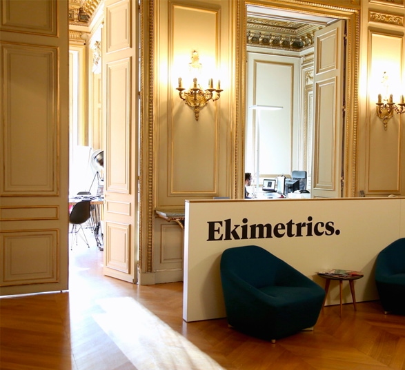 banque accueil ekimetrics avec des poufs et luminaires dans une grande pièce avec de hauts plafonds