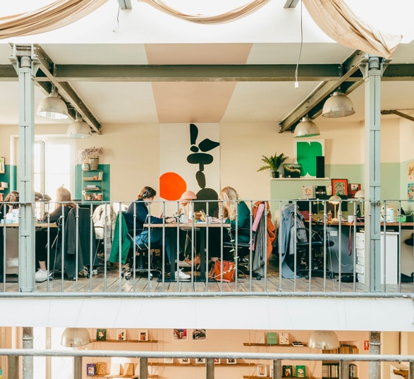 des personnes travaillent dans un bureau partagé type open space à l'étage d'un immeuble décoré