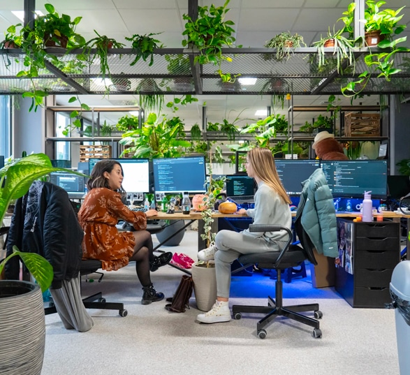 bureaux partagés en open space avec deux femmes qui discutent et de nombreuses plantes du sol au plafond