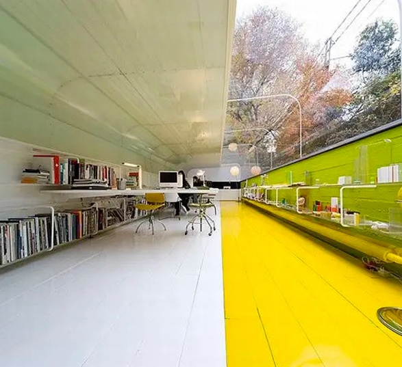un espace de travail séparé en deux, un côté blanc avec bureaux et un côté jaune et vert