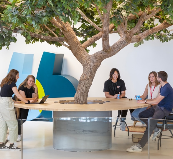 une table de réunion avec un arbre au milieu et des personnes qui discutent autour