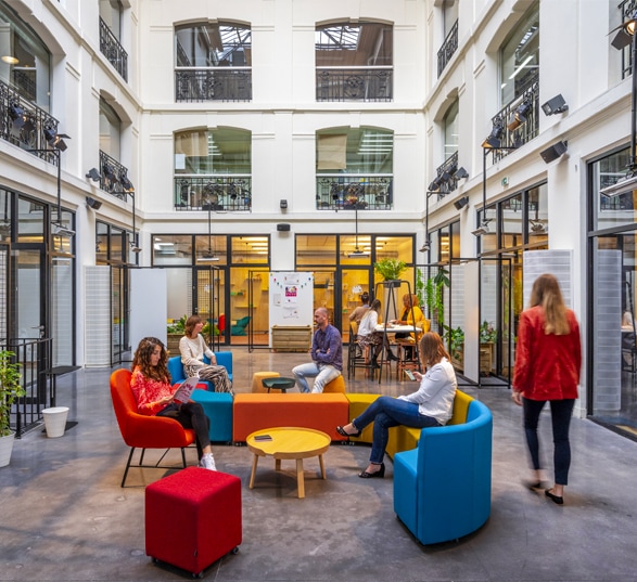 des personnes sont assises dans un canapé modulaire coloré d'un grand hall d'accueil