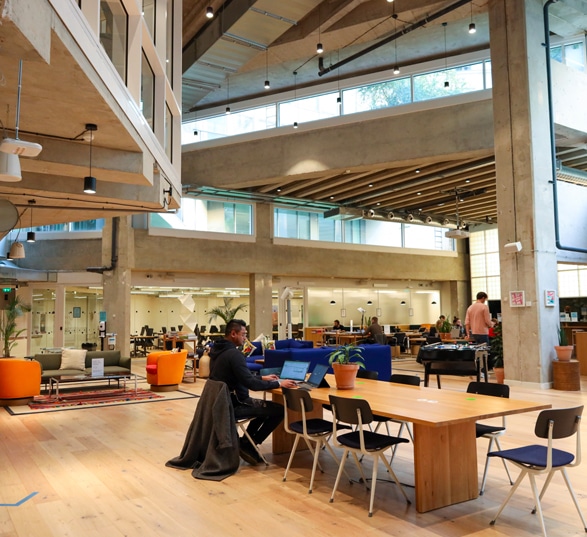 des personnes travaillent dans un grand open space meublé avec des tables et des chaises