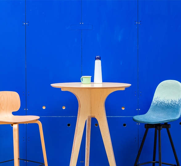 une table haute en bois, une chaise haute en bois et une chaise haute bleu en matériaux recyclés