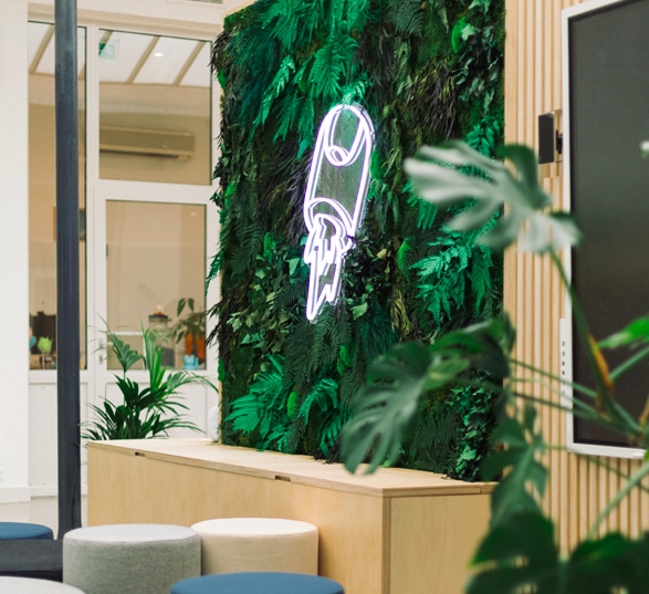 Amanegement d'un hall d'entrée en entreprise avec plantes vertes et logo de l'entreprise.