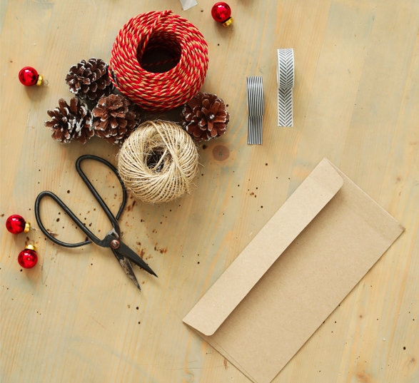 Matériels pour fabriquer des cartes de voeux pour Noël : ciseaux, rubans, végétaux, enveloppe.,