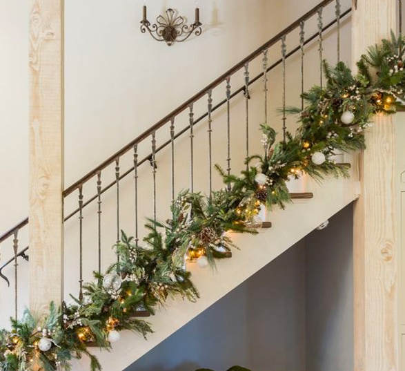 Escalier décoré pour Noël avec des végétaux, des guirlandes lumineuses et des boules de Noël
