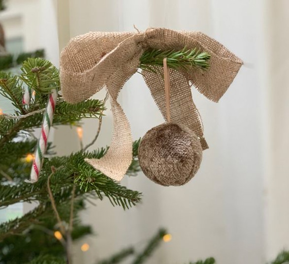 Un sapin de Noël avec une guirlande en noeud en toile de jute.
