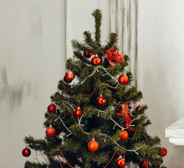 Sapin de Noël décoré avec des boules rouges et des guirlandes.