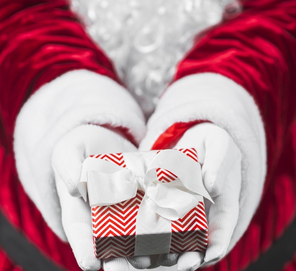 Un père Noël tient dans ses mains un cadeau.