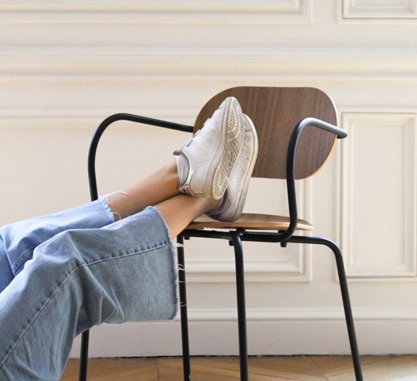 Chaise en bois et métal avec des pieds posés sur l'assise.